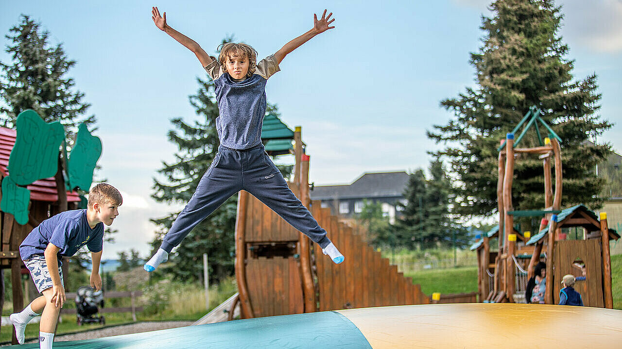 Ein Junge springt auf dem Riesenjumpkissen des Elldus Outdoorspielplatzes hoch in die Luft.