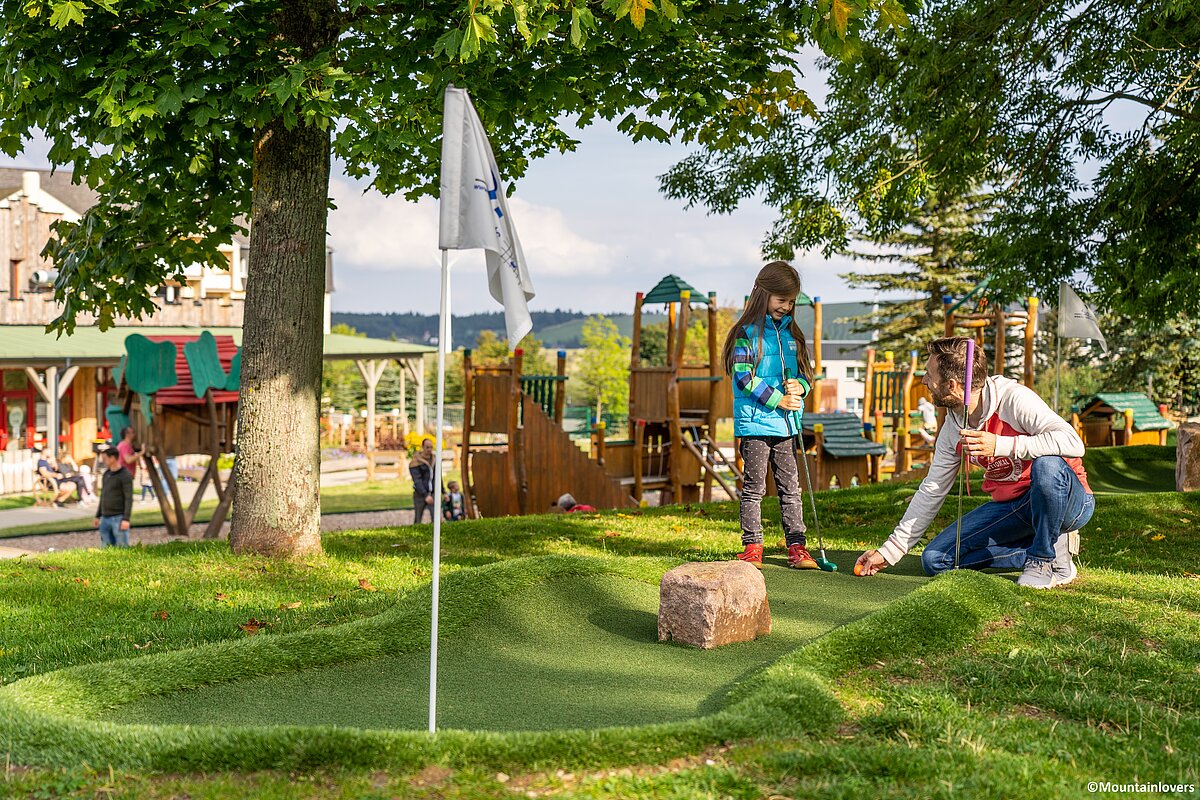 Papa und Tochter auf der Adventure-Minigolfanlage im Outdoorbereich der Elldus Spielscheune.